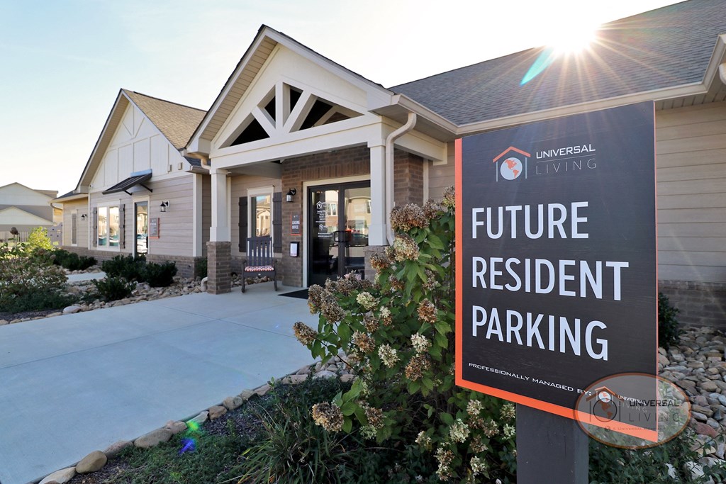 A close up of a tan clubhouse with a sign that reads "Future Resident Parking."