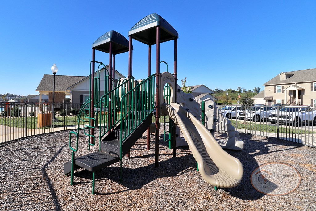 A close up of the fenced in playground with slide and jungle gym.