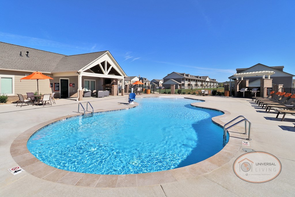 A zero entry pool with lounge chairs and apartments in the background.