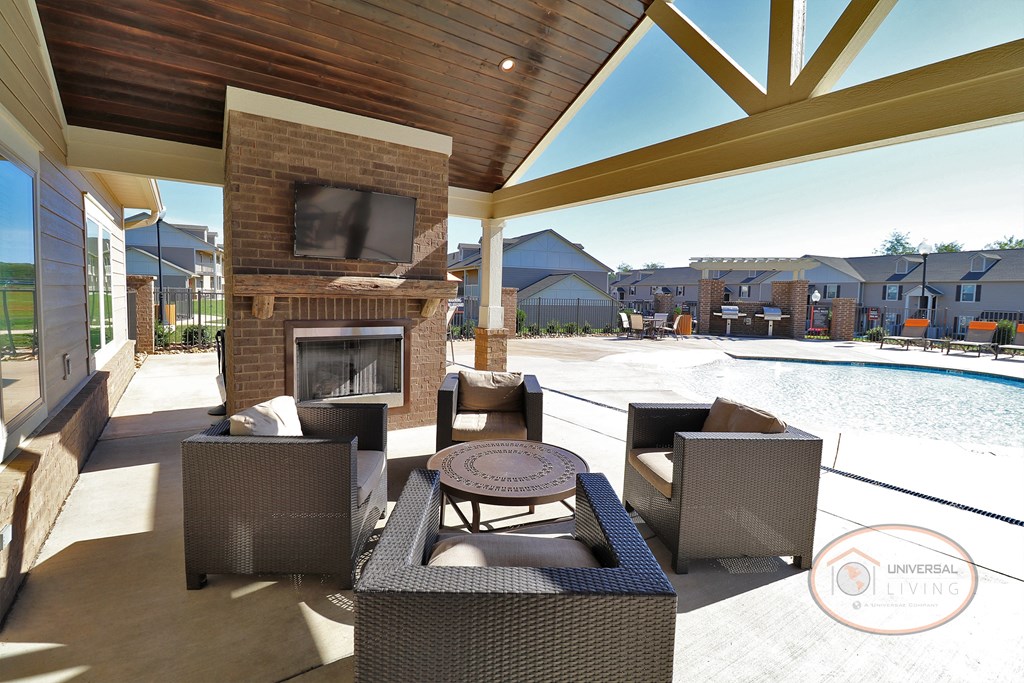 The poolside lounge, complete with fireplace, flat screen TV, lounge seating, and a ceiling fan.