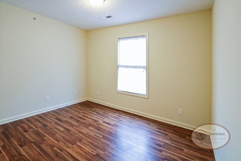 the living room of a home with wood flooring and a window