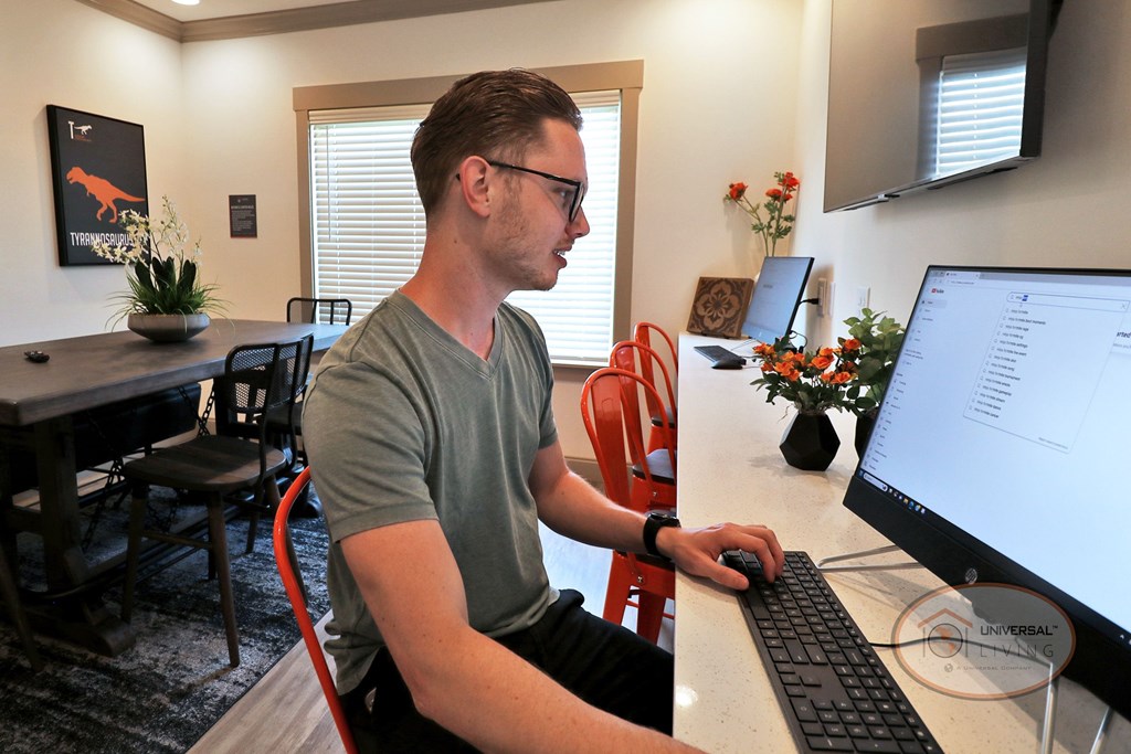 A man sits at a desk in the business center and uses a computer.