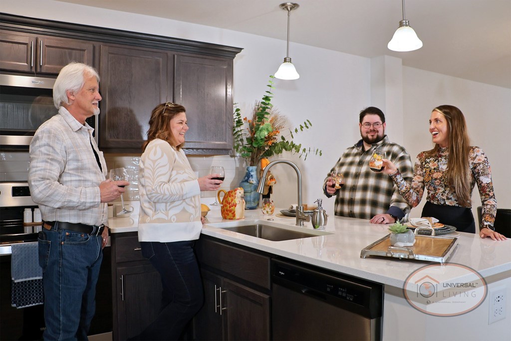 Four people standing in a kitchen enjoying wine and chatting.