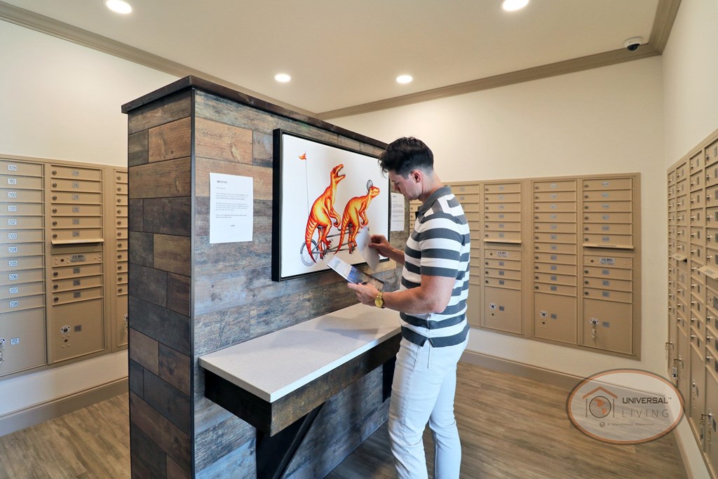 A man standing in front of the table in the mail room, looking through mail.