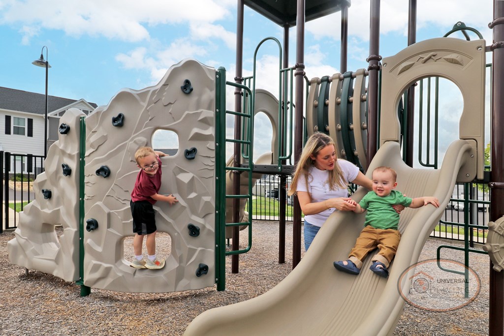 A woman and two children are playing on a slide at the playgorund.