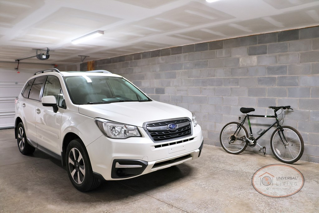 A white SUV is parked in a garage next to a bicycle.