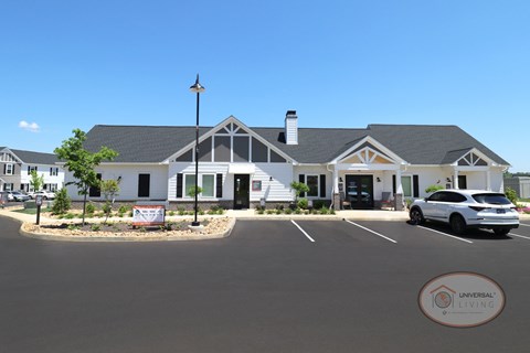 The exterior of a grey and white clubhouse with parking.