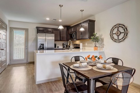 A modern kitchen with a dining table set for two.