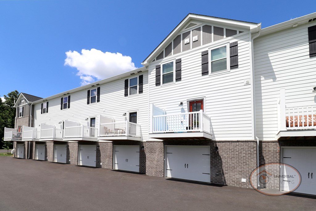 A white apartment building with balconies and drive under garages.