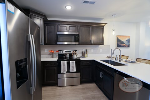 A kitchen with a stainless steel refrigerator and black cabinets.