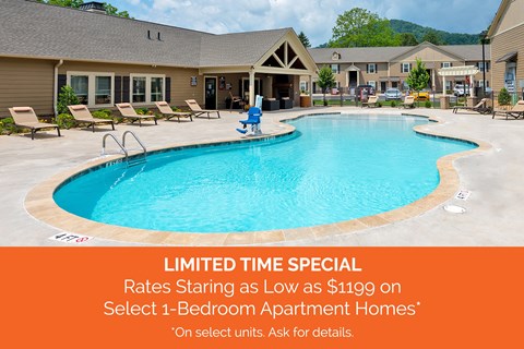A pool surrounded by lounge chairs and a building in the background with a sign advertising a special rate.