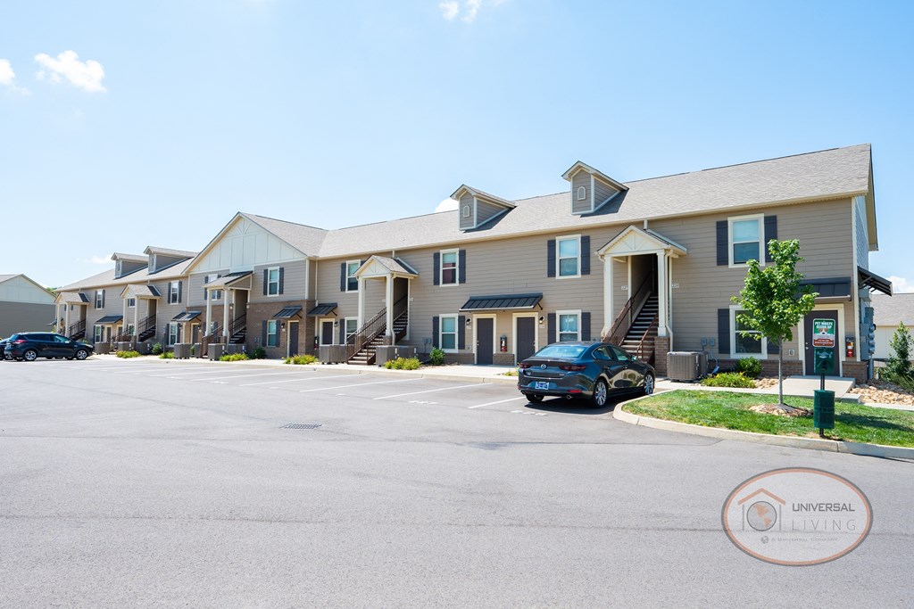 a row of apartment buildings with a car parked in a parking lot