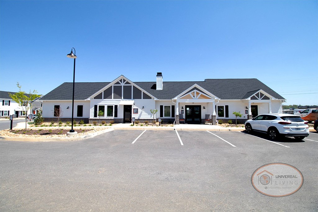a large white house with a parking lot and a car