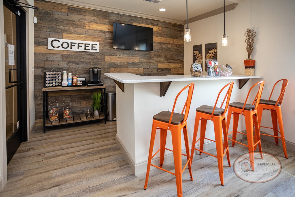 a kitchen with orange stools and a bar with a coffee shop on the wall