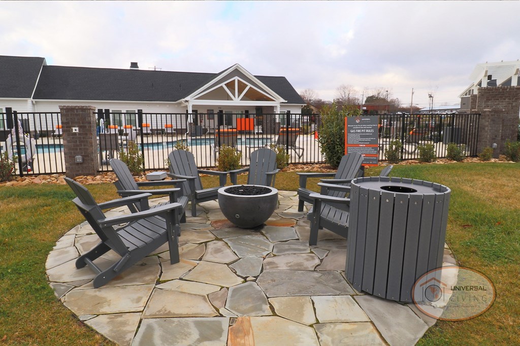 a patio with chairs and a fire pit in front of a pool