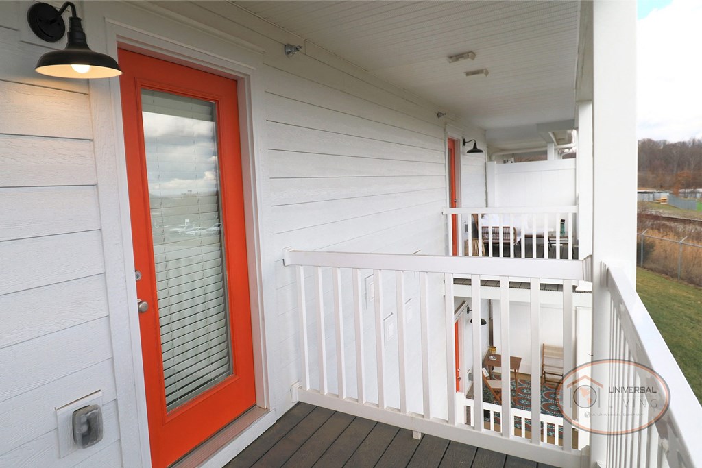 a red door on the porch of a white house