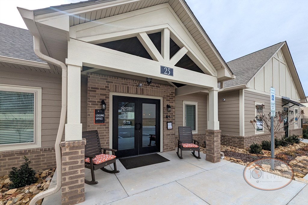 the front door of a building with a porch and two benches