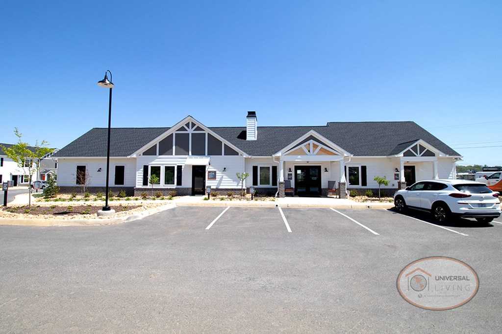 a large white house with a parking lot and a car