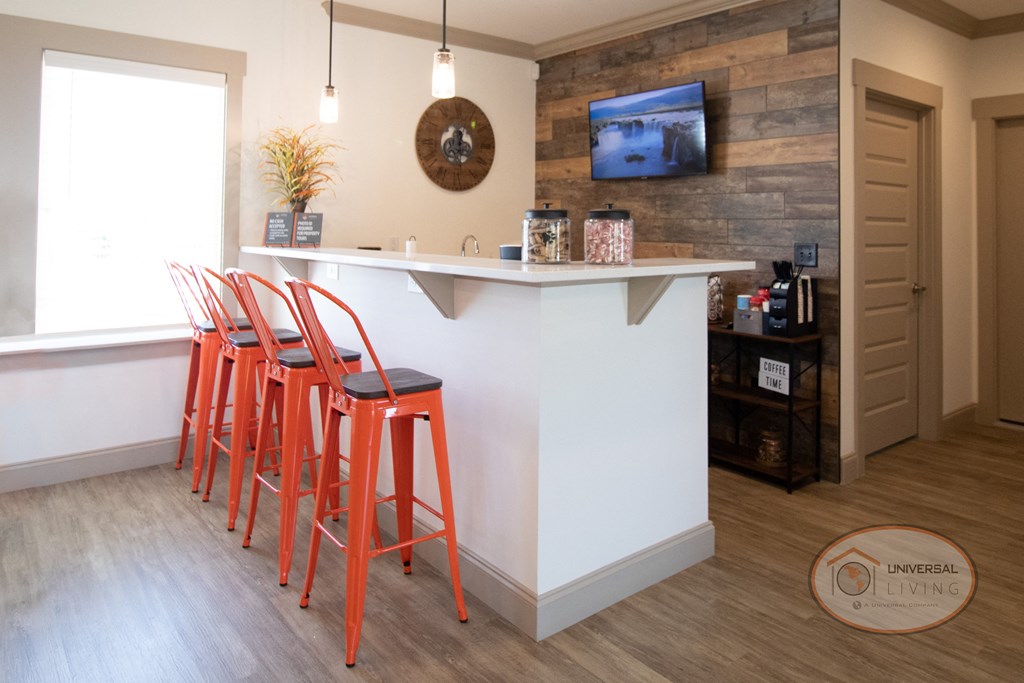 A coffee bar with flat screen TV, coffee machine, and barstool seating.