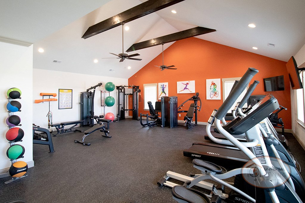 the gym has plenty of exercise equipment and a ceiling fan