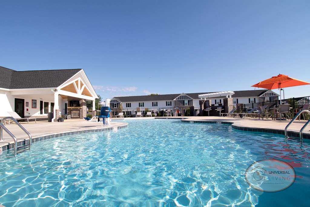 A swimming pool in front of clubhouse, surrounded by lounge chairs and umbrellas.