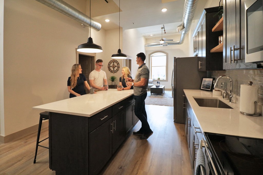 A group of people standing around a kitchen island talking.