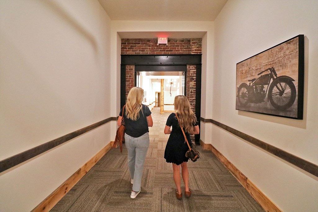 Two women walking down a hall through a brick doorway.
