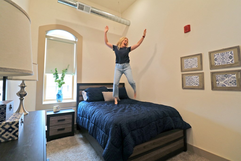 a woman jumping on a bed in a bedroom