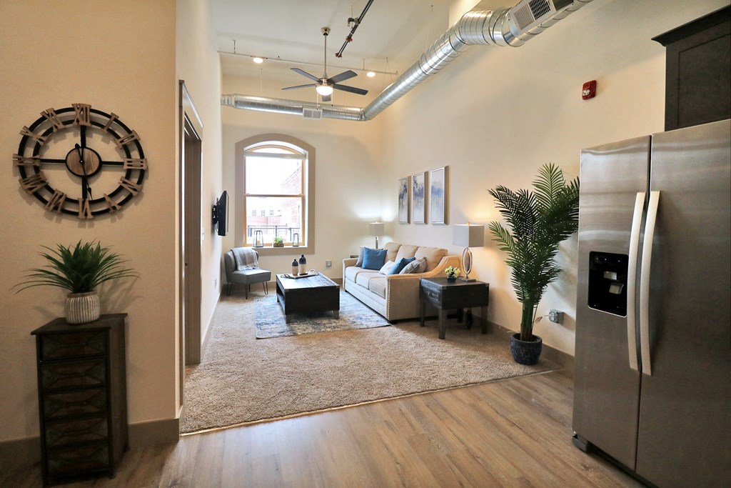 A living room with carpet, white walls, and a large window.