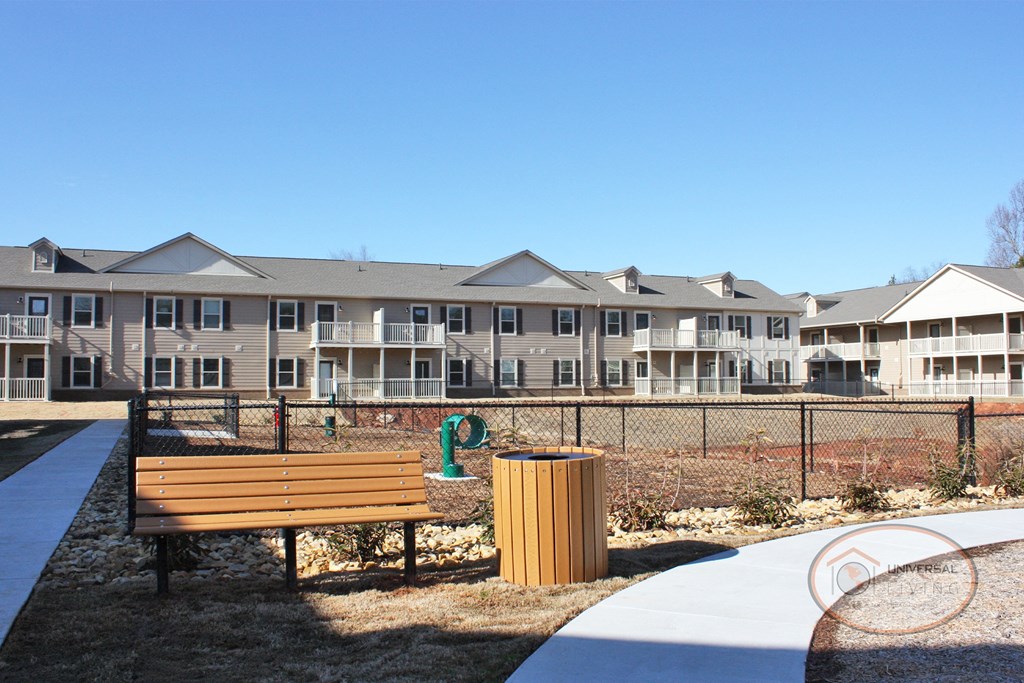 A dog park with seating, water station for pets, pet waste pick-up station, and obstacles for your dog to play on.
