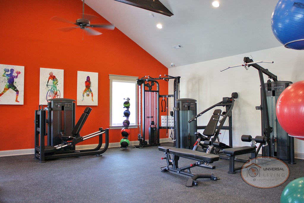 A fitness center with weight training and cardio equipment with an orange accent wall.
