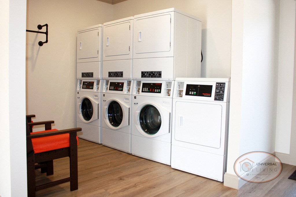 An on-site laundry facility with washers, dryers, a side table, and coat rack.