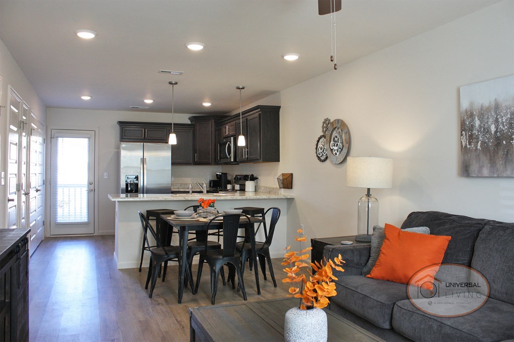 An apartment home living area and kitchen with patio door in background.