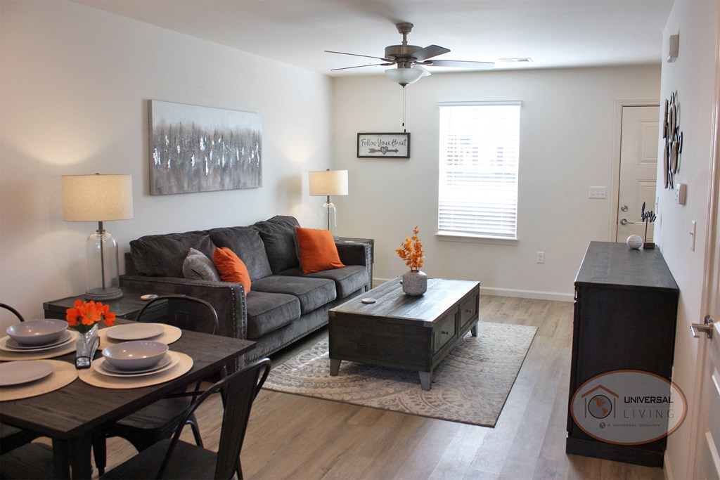 A living room with white walls, dark hardwood style vinyl flooring, and abundant natural light.