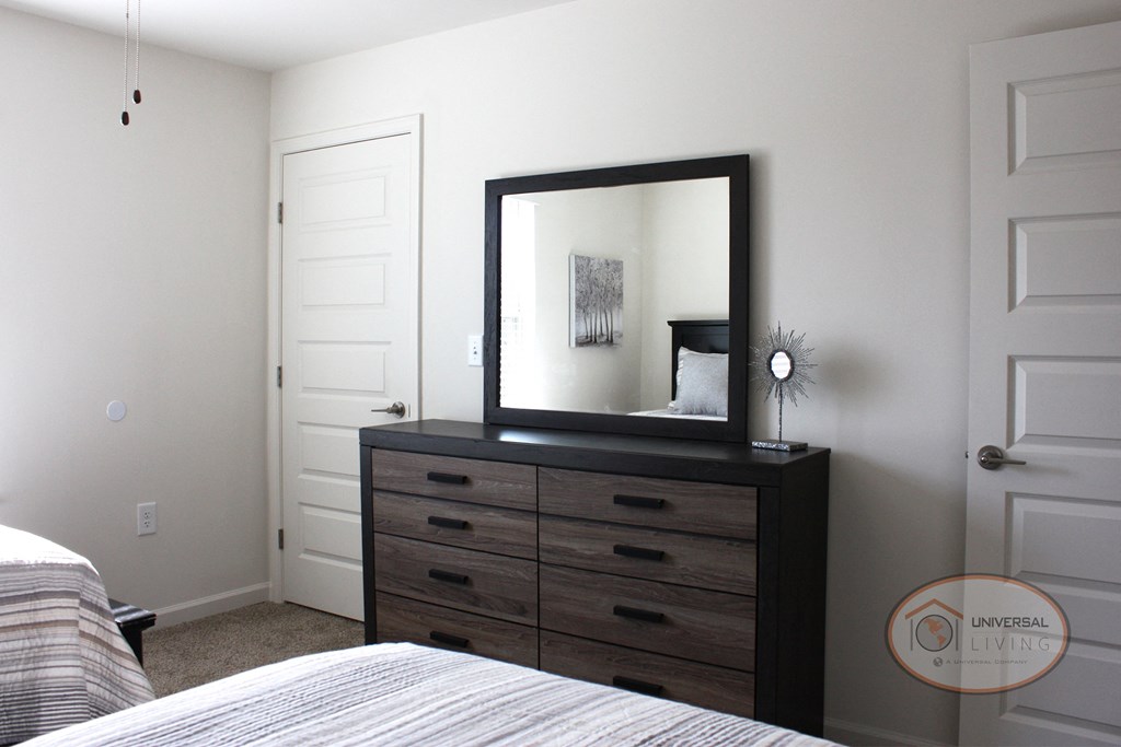 A bedroom with two twins beds, carpet, and a dresser.
