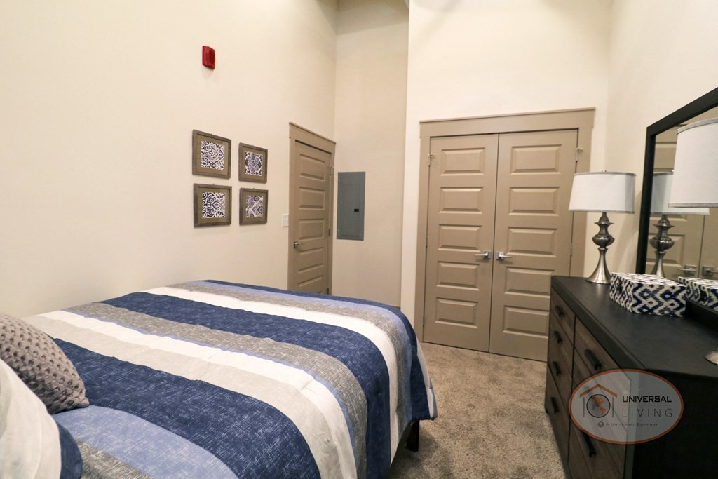 A bedroom with a queen size bed, carpet, and white walls.