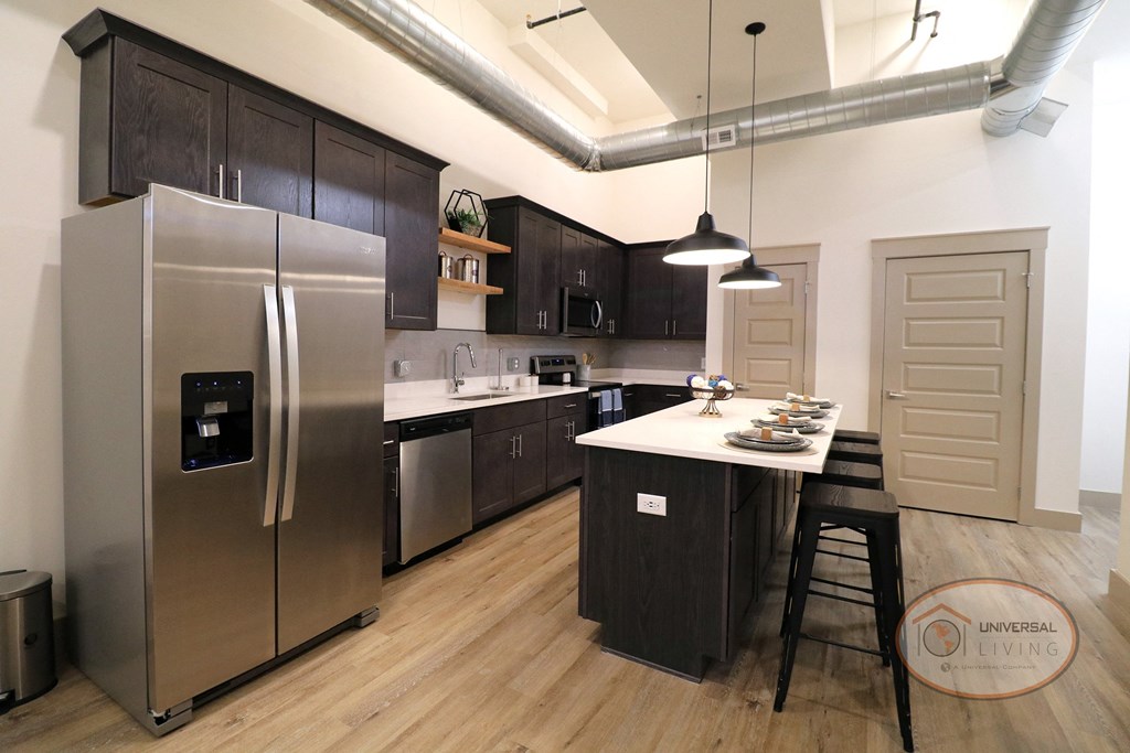 A large kitchen with stainless steel appliances and white counters with dark cabinets.