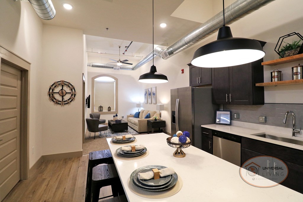 A kitchen with light counters, vinyl hardwood flooring, and white walls.