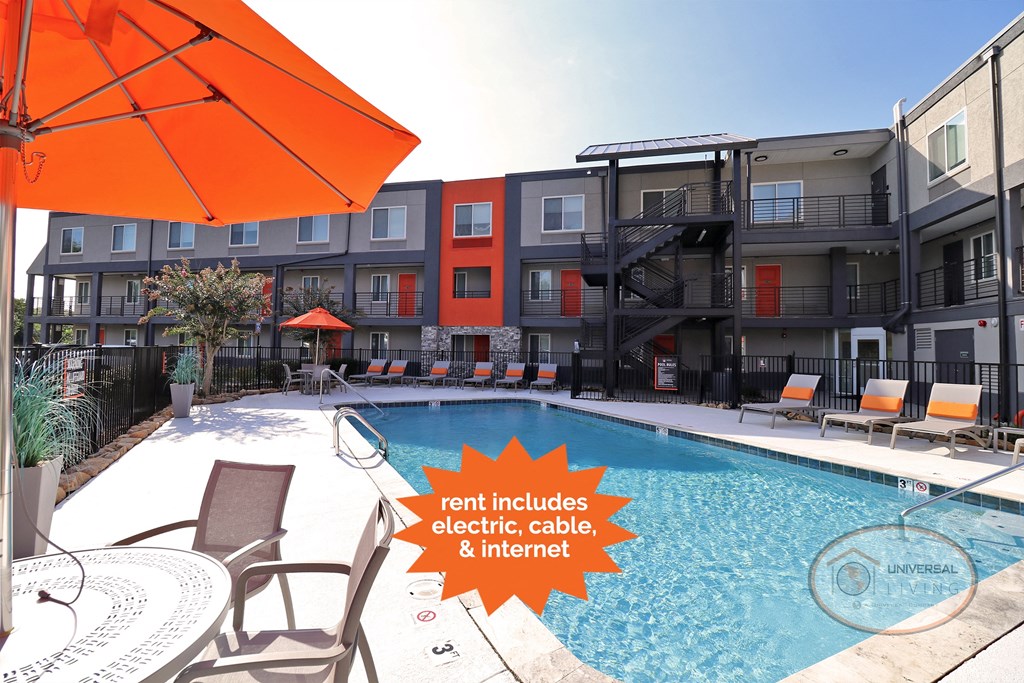 a pool with an orange umbrella next to an apartment building