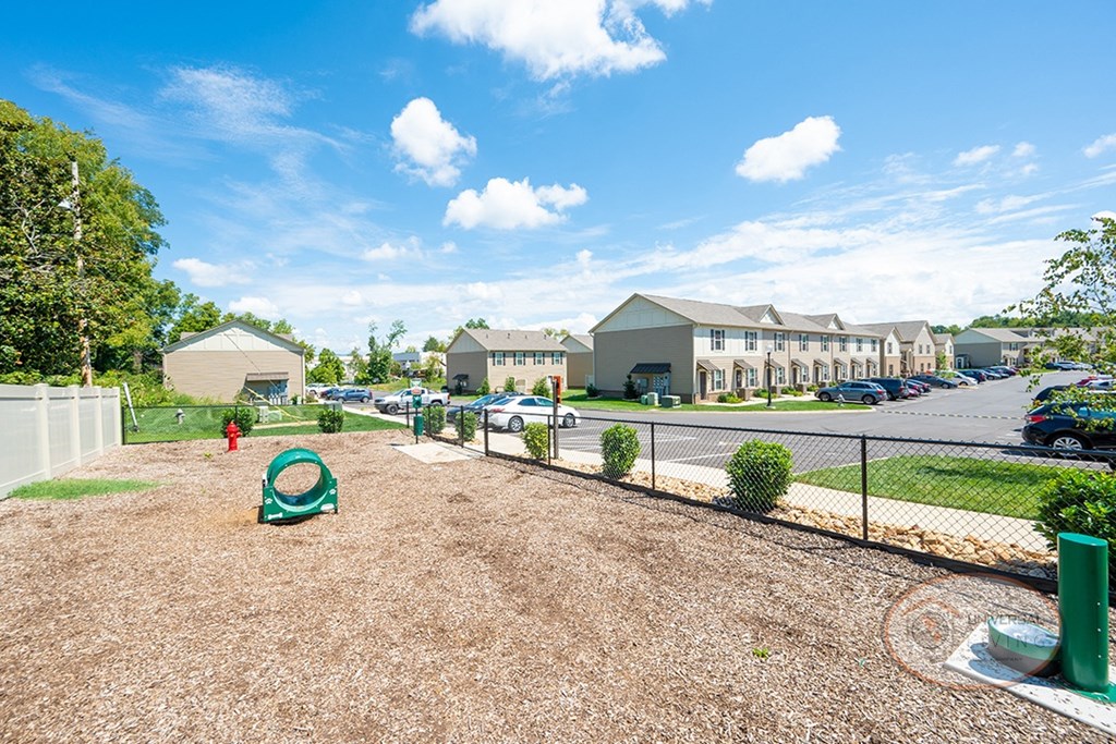 A dog park with seating, water station for pets, pet waste pick-up station, and obstacles for your dog to play on.