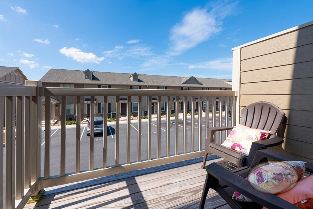 A balcony with seating a a view of the apartment community.
