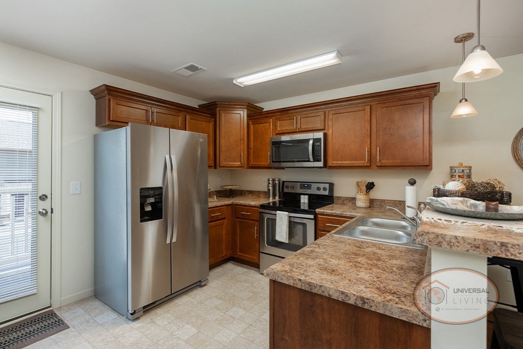 A kitchen with dark granite countertops, dark cabinets, and stainless steel appliances.
