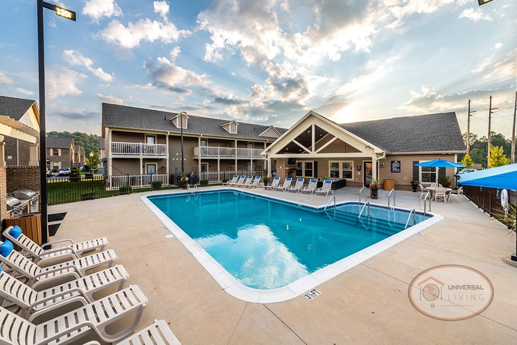 A swimming pool in front of clubhouse, surrounded by lounge chairs and umbrellas.