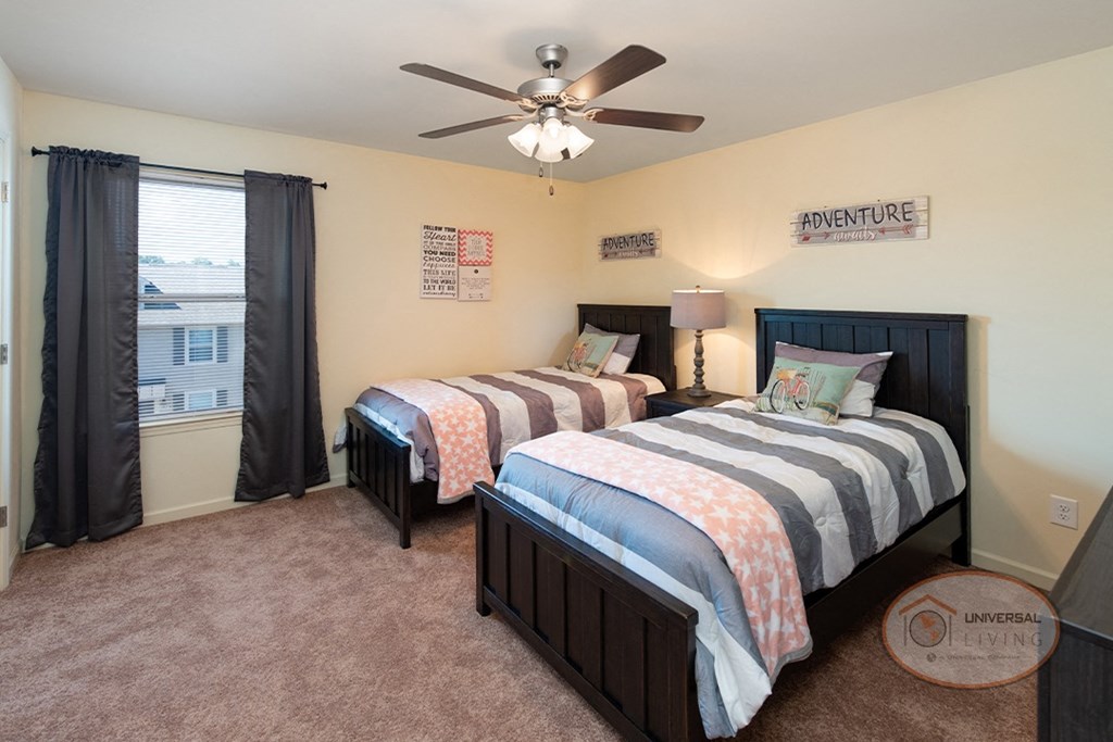 A bedroom with two twins beds, carpet, and a dresser.