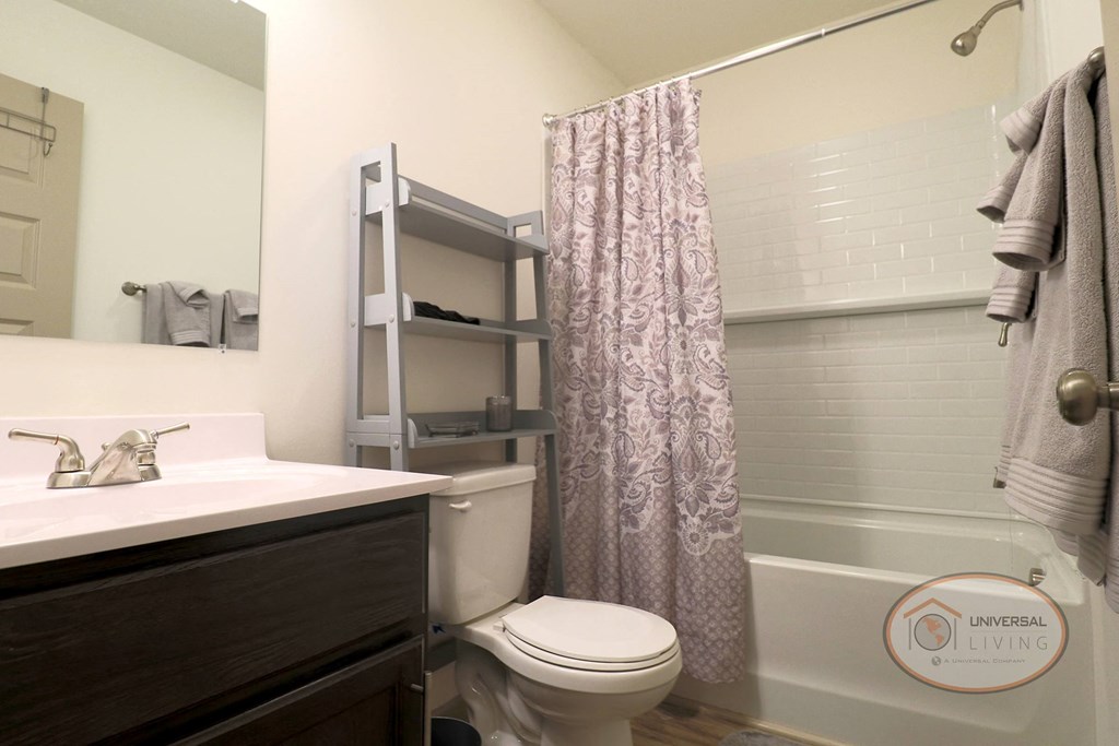 a bathroom with a toilet sink and shower and a shower curtain
