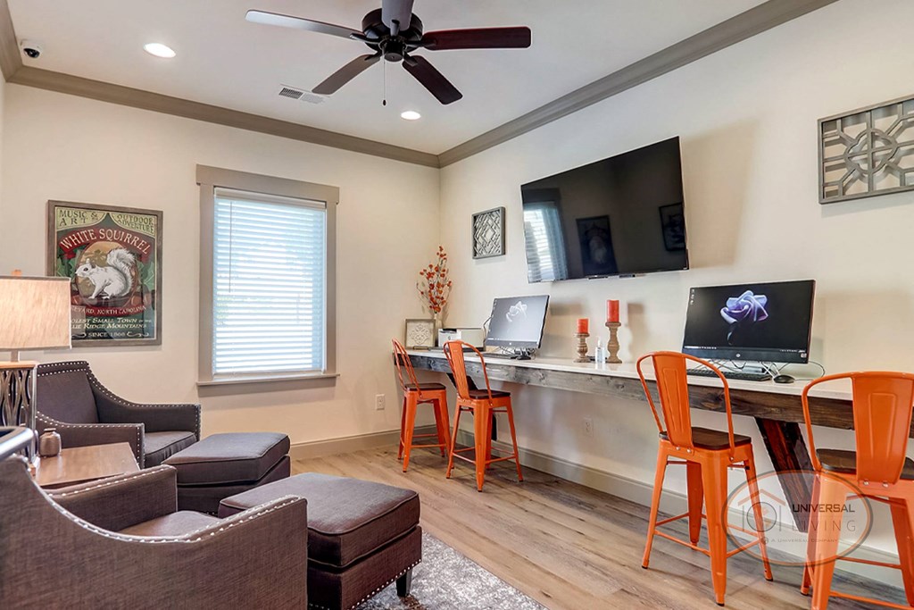 a living room with a couch and a desk with two computers
