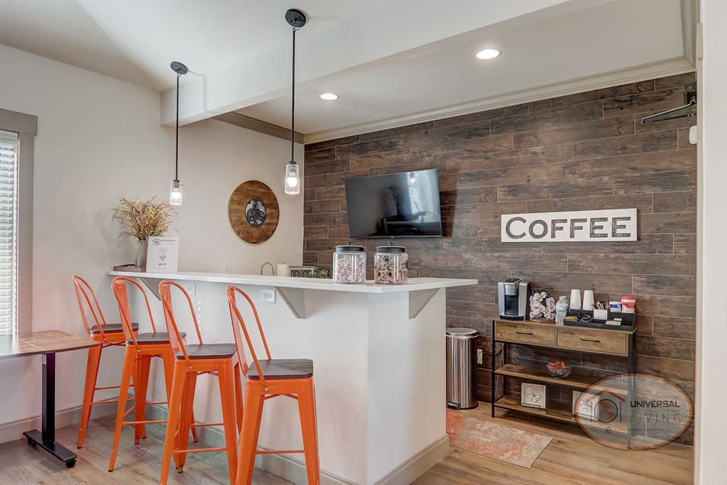a bar with four orange stools in front of a counter with a coffee shop