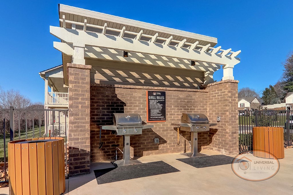 a brick building with a barbecue grill and a wooden pergola