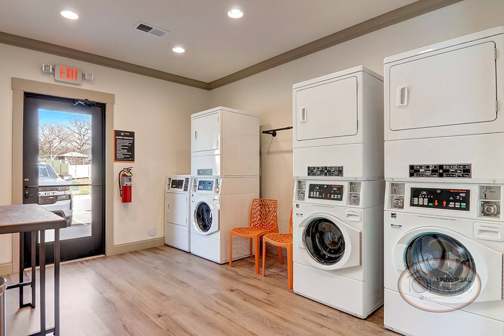a laundry room with washer and dryers and a table with a chair