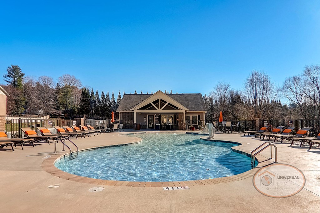 a resort style pool with orange chairs and a building in the background